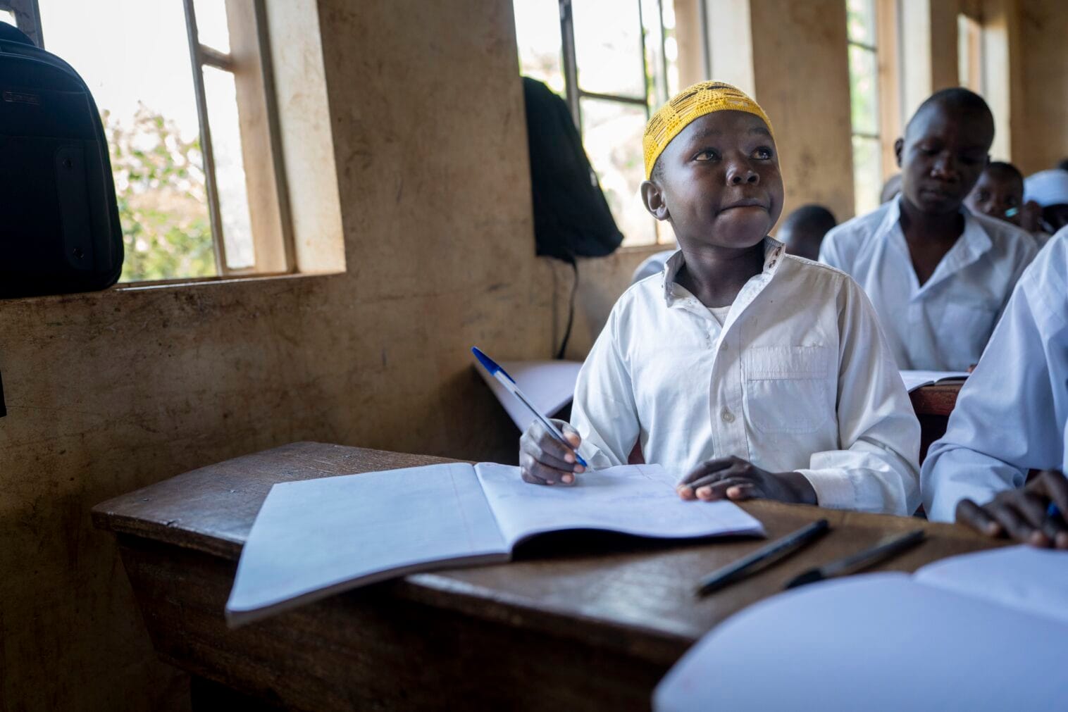 Oppilas istuu pulpetin ääressä, edessään pöydällä auki kirjoja.