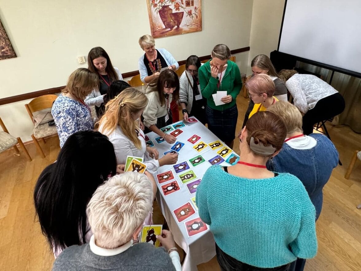Ihmisiä kokoontuneena pöydän ympärille psykososiaalisen tuen koulutuksessa.
