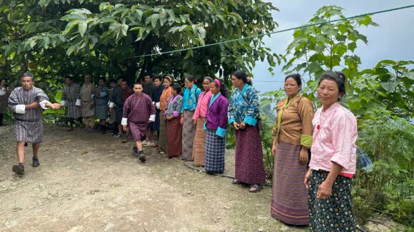 A row of Bhutanese women and men in colourful costumes.