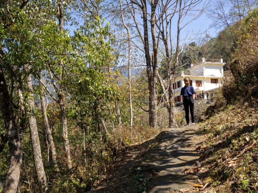 Koulutyttö seisoo vuorenrinnettä nousevalla tiellä.