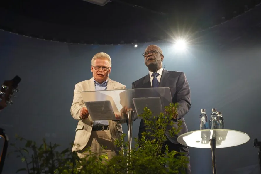 Denis Mukwege pitämässä puhetta lavalla, vierellään tulkki.