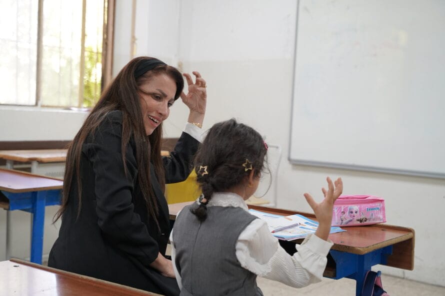 Erityisopettaja istuu samassa pulpetissa oppilaan kanssa ja he molemmat elehtivät ajatuskuplaa.