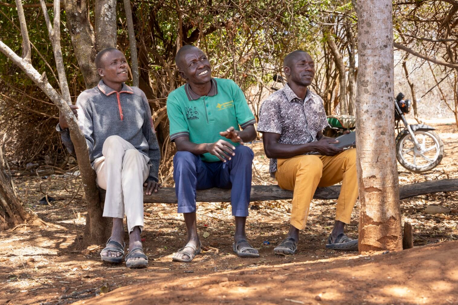 Kolme pokotmiestä istumassa puunrungon päällä.