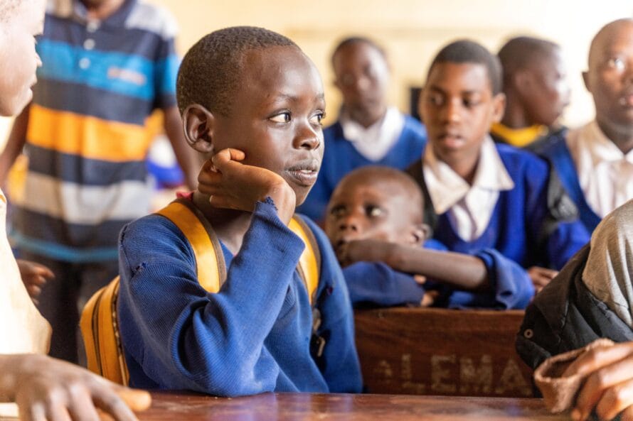Vammaisia lapsia koululuokassa Tansaniassa, päällään siniset koulupuvut.