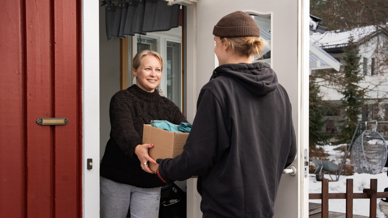 Nainen ojentaa pahvilaatikkoa miehelle.