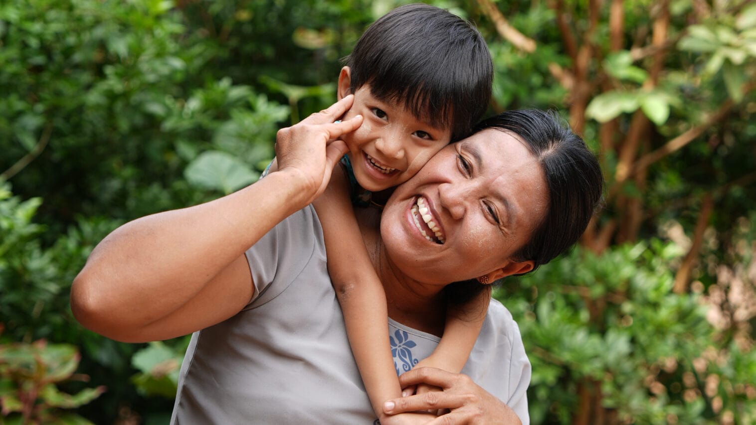 Naurava pieni poika halaa iloista äitiään.
