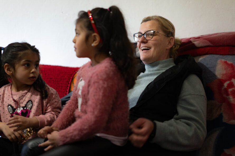 Two Roma girls and a woman sitting on a sofa.