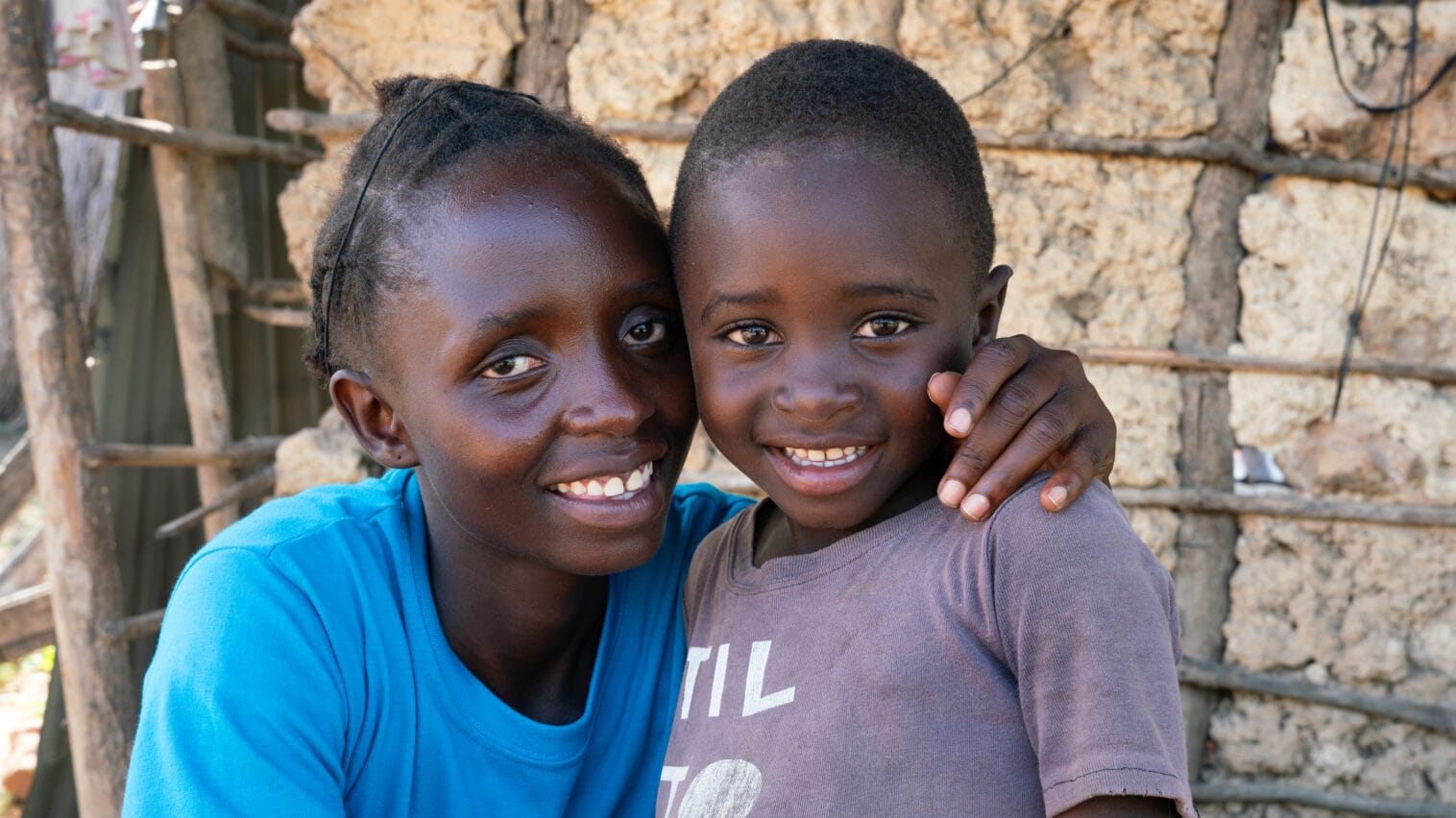 Sinipaitainen nainen halaa poikaansa ja molemmat hymyilevät kameralle.