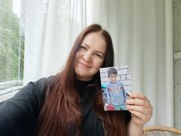 Nainen pitää valokuvaa kädessään, jossa on hänen kummilapsensa