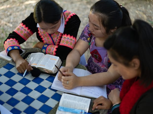 Tyttöjä turkii ryhmässä raamattua saman pöydän ääressä.