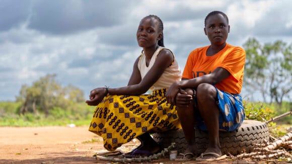 Kaksi kenialaista tyttöä istuu autonrenkaan päällä.