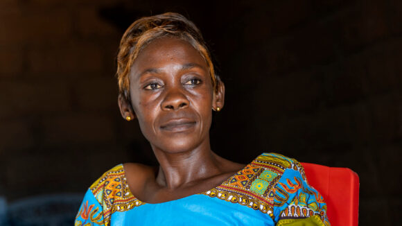 Congolese woman sitting in turquoise outfit.