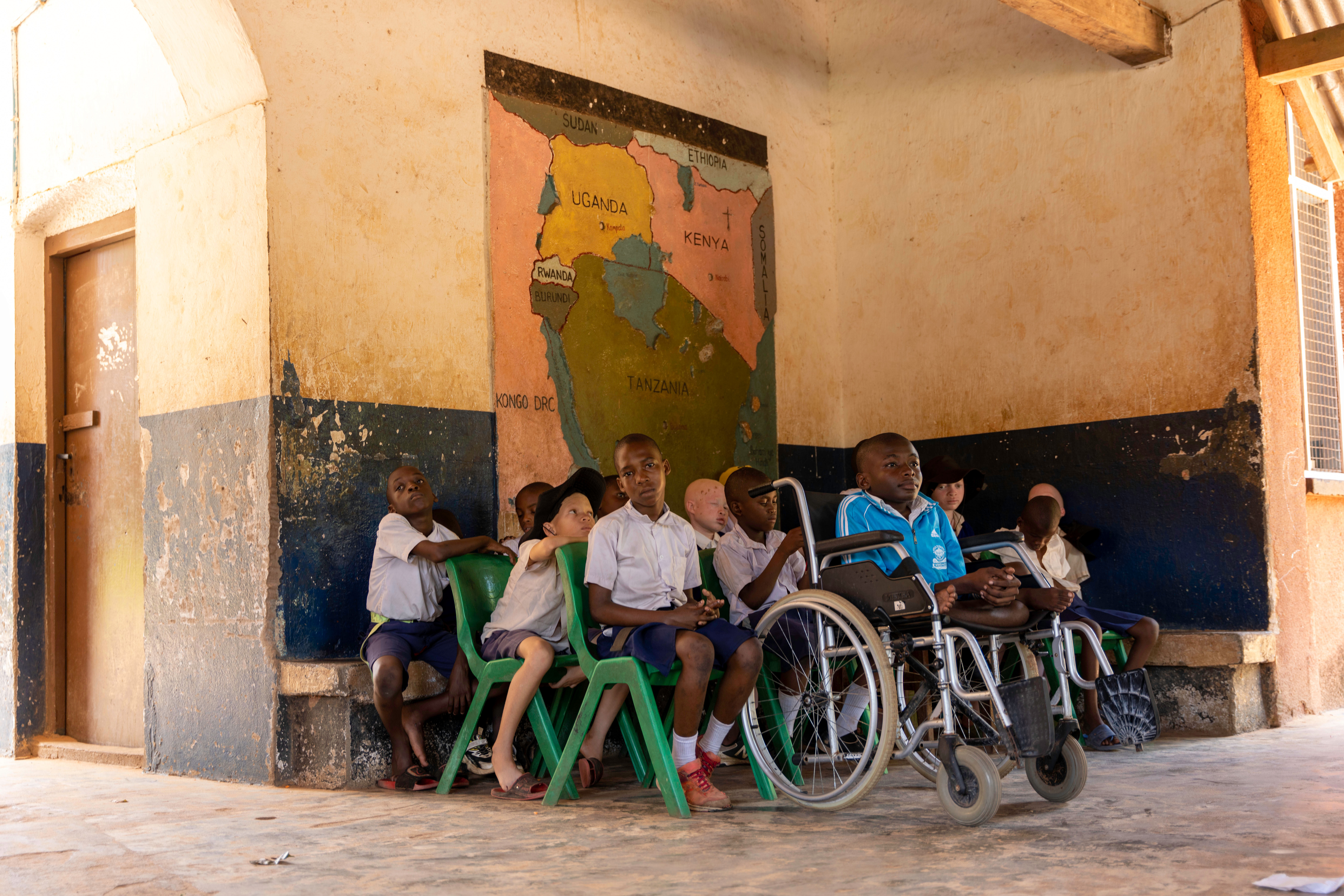 Oppilaita istumassa tuoleilla ja pyörätuoleissa koulun käytävällä.