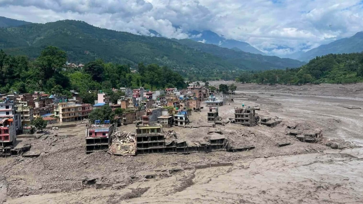 Nepalin tulvan tuhoama kylä ja mutainen vesimassa.