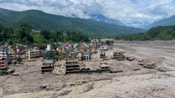 Nepalin tulvan tuhoama kylä ja mutainen vesimassa.