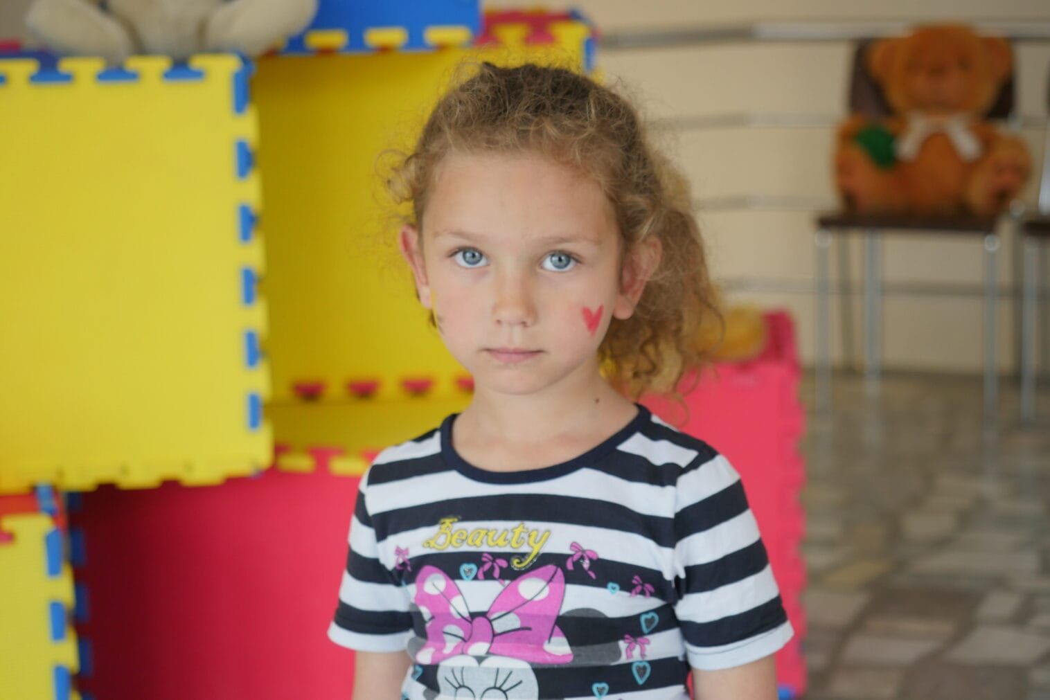 Tyttö seisoo ja katsoo kameraan