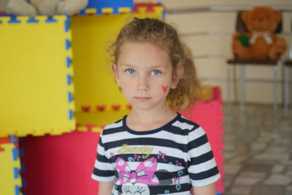 Tyttö seisoo ja katsoo kameraan