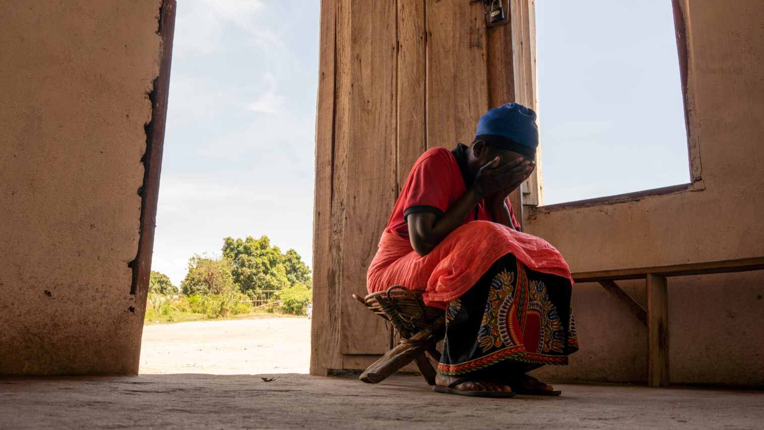 A woman dressed in red covering her face with her hands.