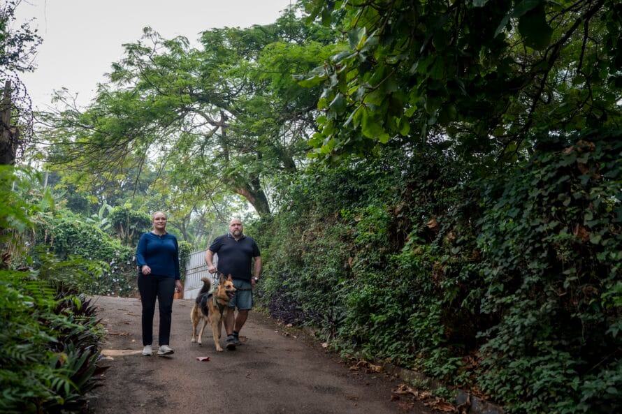 Susanna ja Adam Sorila lenkillä vehreässä maastossa saksanpaimenkoiransa kanssa.