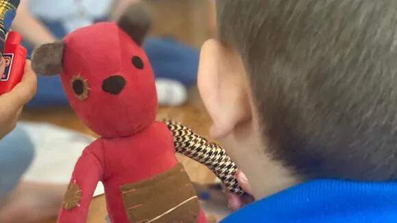The child is holding a teddy bear.