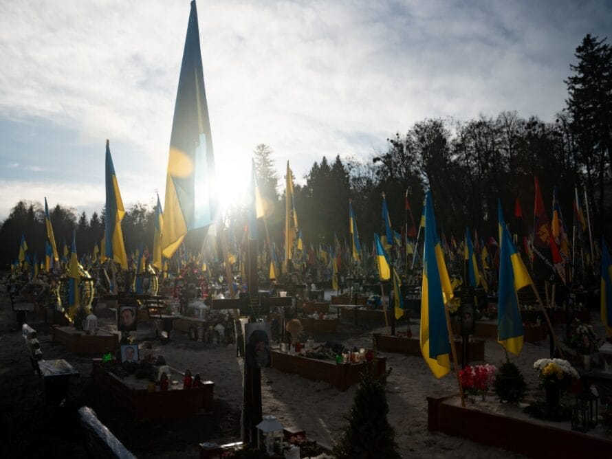 Ukrainan lippuja ja kukkakimppuja sotahautausmaalla.