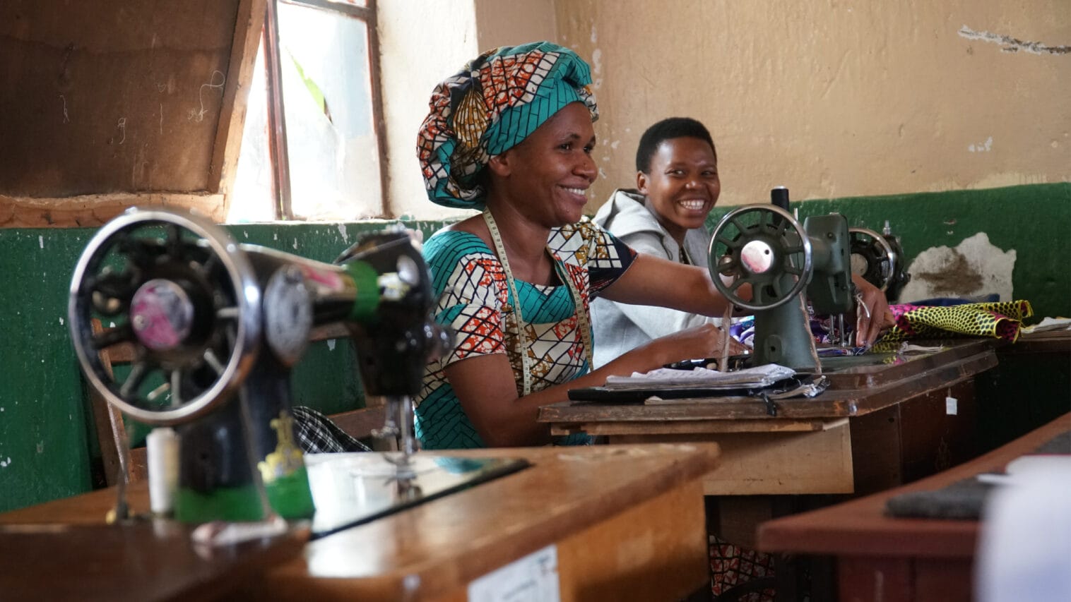 A woman in a colorful outfit sews with a sewing machine.