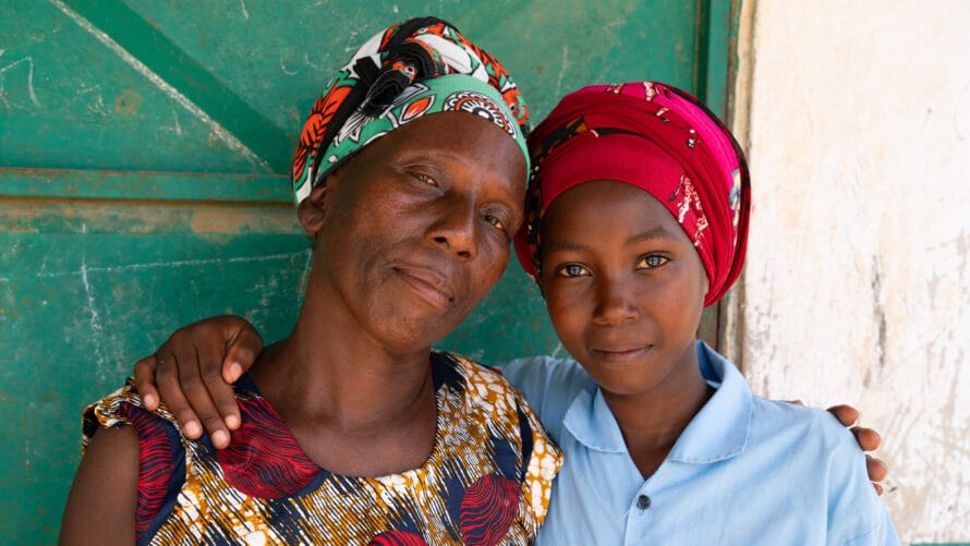 Kenialainen äiti ja tytär katsovat kameraan ja halaavat.