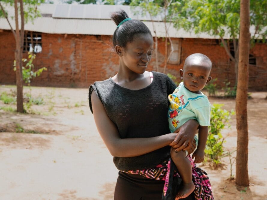 Nuori kenialainen äiti pitää lasta sylissään.