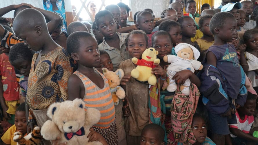 A group of children stand with cuddly toys in their hands.