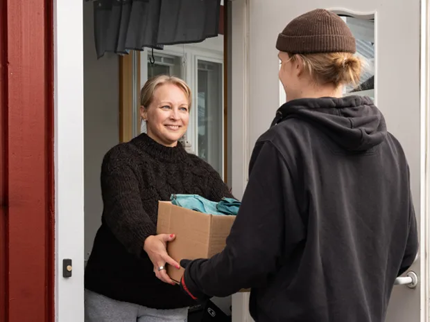 Secondhandin noutopalvelun kuljettaja hakee paketin asiakkaan kotiovelta.