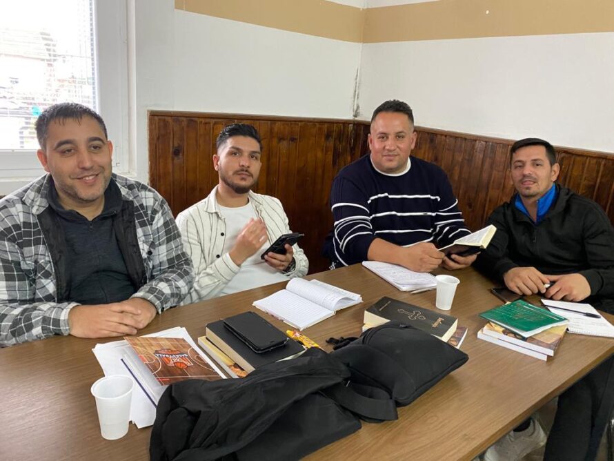 Bible school, four men sitting side by side at a table.