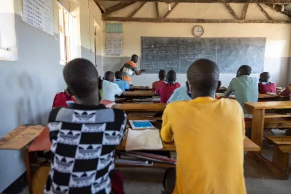 Yläkoulun opettaja opettaa luokan edessä ugandalaisessa koulussa