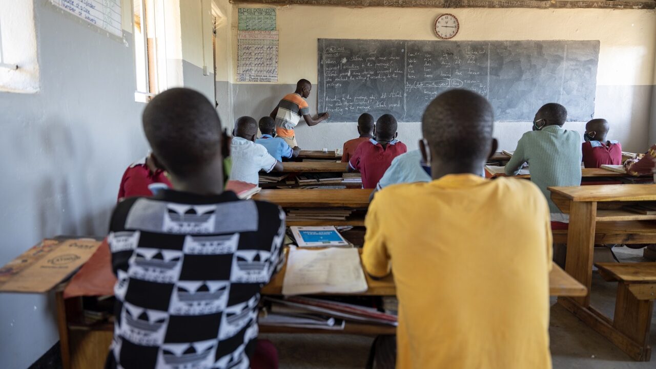 Yläkoulun opettaja opettaa luokan edessä ugandalaisessa koulussa